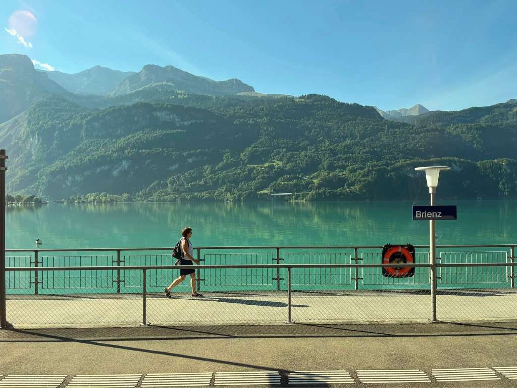 A person walking in front of a turquoise lake in switzerland