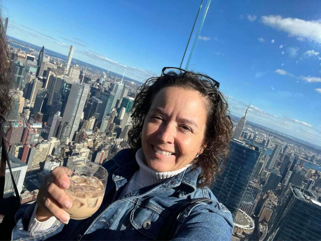 woman holding drink on rooftop with NYC skyline