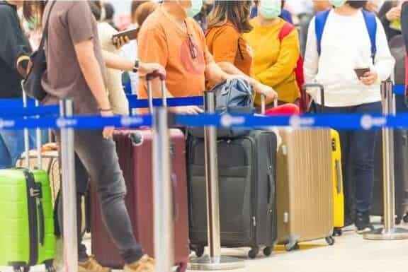 people waiting in line with luggage at airport